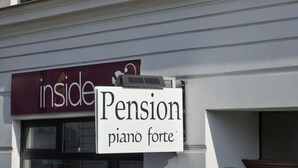 Eine Gebäudefassade mit einem Schild für "Pension piano forte" und einem Schild mit dem Hinweis "drinnen".