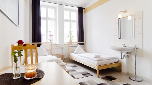 Ein Schlafzimmer mit einem Einzelbett, einem Nachttisch mit Kerze, einem Stuhl und einem Fenster mit Vorhängen.