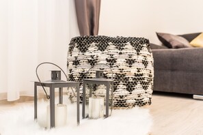 A cozy living room with a grey sofa, a woven ottoman, and two black lanterns on a fluffy white rug. - Villa Rossa (Pasman)