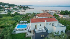 Une maison moderne dotée d’une piscine, d’un balcon avec mobilier d’extérieur et offrant une vue sur la mer.