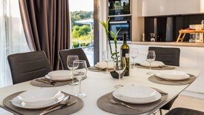 Une table à manger dressée avec des assiettes, des couverts et des verres à vin, une bouteille de vin et une plante placés sur la table.