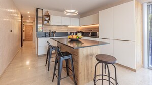 A modern kitchen with a central island, bar stools, and a built-in oven.