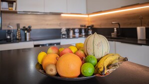 A bowl of fruits on a kitchen counter with a modern kitchen in the background.