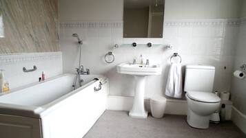 A bathroom with a bathtub, sink, mirror, toilet, and a towel rack.