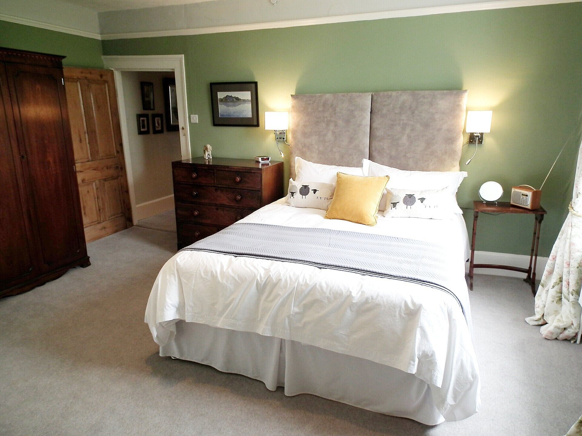 A bedroom with a bed, dresser, nightstand, lamp, and a picture on the wall.
