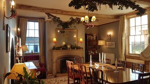 Un coin repas agrémenté d’une cheminée, de meubles en bois et d’un lustre.
