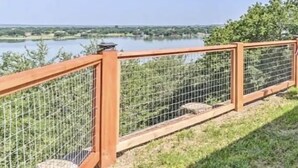 Una cerca de madera con vista a un cuerpo de agua bajo un cielo despejado.
