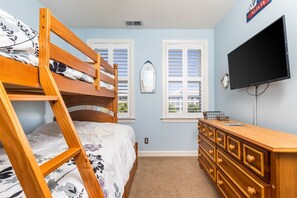 A bedroom with a bunk bed, dresser, television, windows, and a mirror.