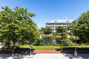 A building with a large lawn, a pond, and trees. - Sunset Island 15 Fountain Drive West (Ocean City)