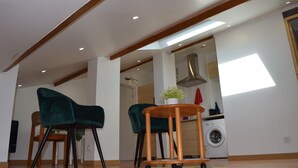 Une cuisine moderne équipée d’un lave-linge, un coin repas avec deux chaises et une petite table agrémentée d’une plante en pot.