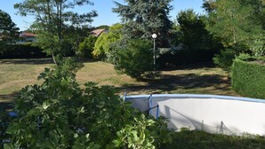 Un jardin à l’arrière de la maison, avec une piscine, entouré de différents arbres et d’une pelouse.