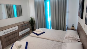Ein Hotelzimmer mit zwei Betten, einem großen Spiegel, einem Deckenventilator und einem fenster mit Vorhängen.