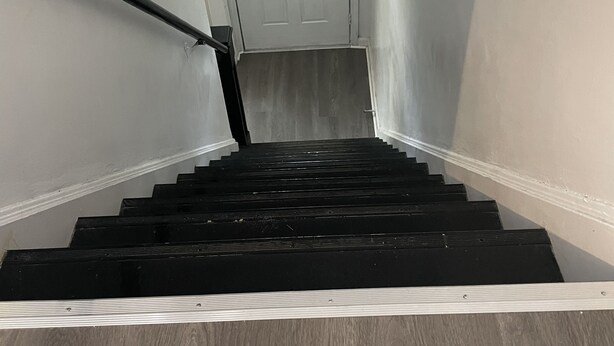 Een trap met een leuning die leidt naar een deur met een raam erboven.