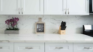A kitchen with white cabinets, a marble countertop, a plant, a chalkboard sign, and a knife block. - New updated 1.5 blocks to beach, 5 min walk, 4 bedroom 3 bath, king size bed,  (Galveston)