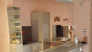 Een kleine keuken met een wit aanrecht, een ingebouwde oven en een wandplank.