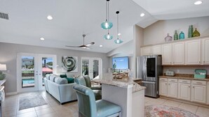 A modern kitchen with a central island, stainless steel appliances, and a dining area with a bar stool.