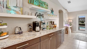 A kitchen with a marble countertop, coffee bar, and a sign that reads "Margarita".