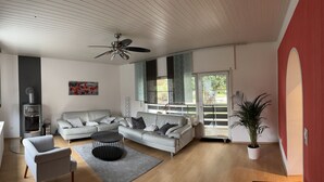 A modern living room with a sofa, armchair, coffee table, and a ceiling fan.