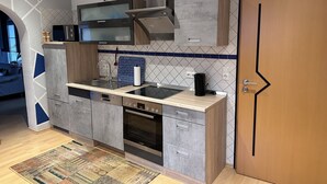 A modern kitchen with a dishwasher, oven, and a coffee maker on the counter.