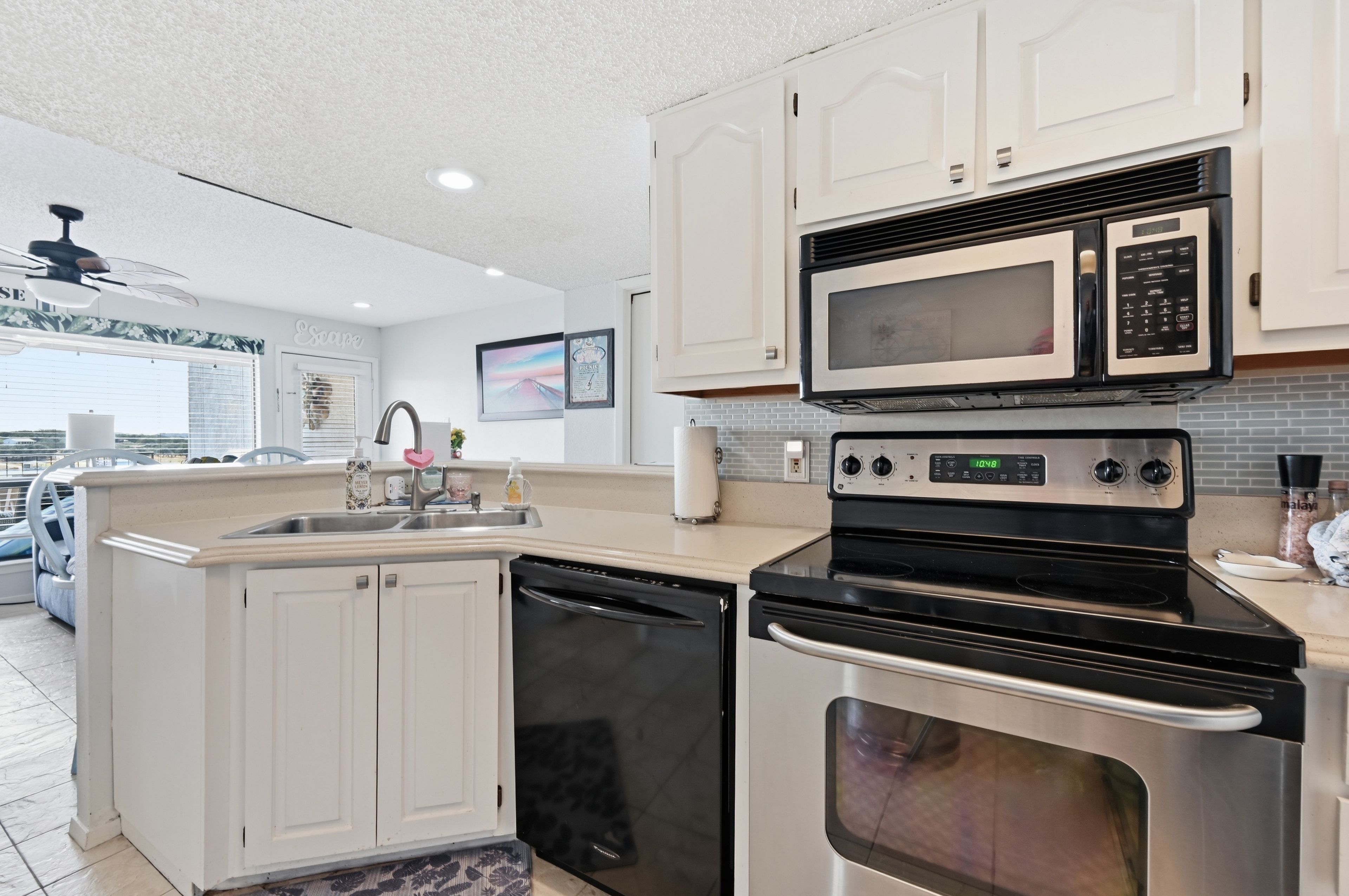 A modern kitchen with white cabinetry, a built-in microwave, a stove, and a dishwasher.