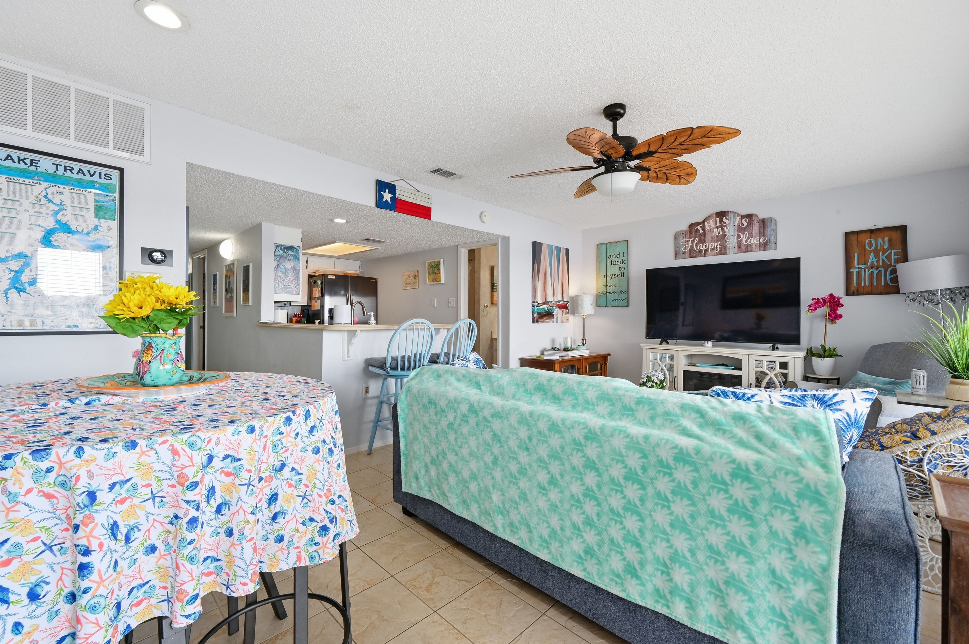 A compact living space with a dining area, a sofa, a television, and a ceiling fan.