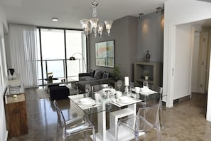 A modern dining area with a glass table, clear chairs, and a chandelier. - Yoo Panama & Arts Tower (Panama City)