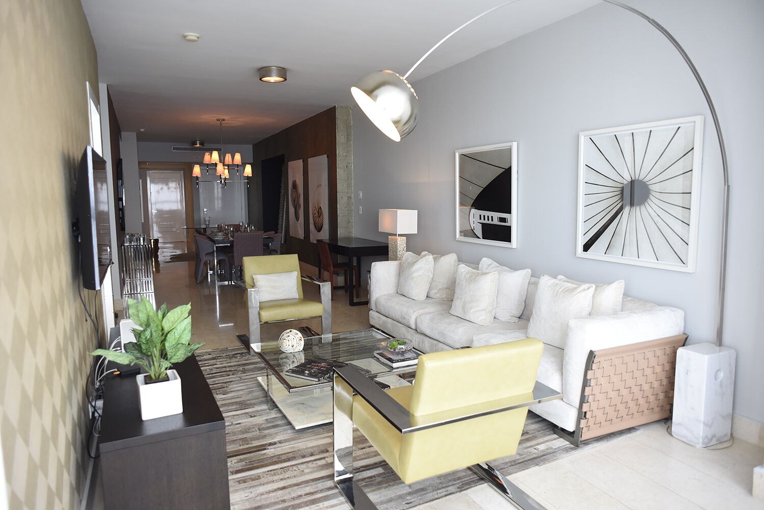 A modern living room with a sofa, armchairs, a coffee table, and a dining area in the background.