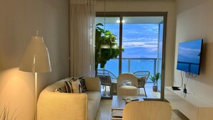 A modern living room with a sofa, chairs, a coffee table, a TV, and a balcony with plants. - Yoo Panama & Arts Tower (Panama City)