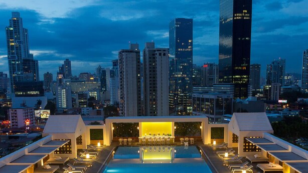 A rooftop pool area with lounge chairs and a bar, surrounded by high-rise buildings. - Yoo Panama & Arts Tower (Panama City)