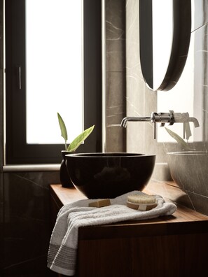 Ein Badezimmer mit einem schwarzen Waschbecken, einer Holzauskleidung, einem Handtuch und einer Pflanze.