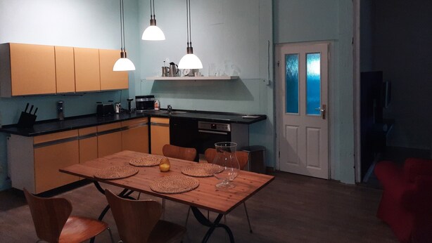 Una cocina compacta con armarios de madera, una mesa de comedor con individuales y iluminación colgante.