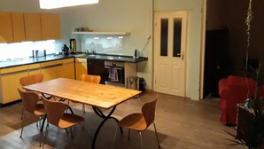 Una cocina moderna con una mesa y sillas de madera, horno empotrado y una lámpara colgante.