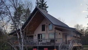 Mökki, jossa on suuri terassi, ulkotila istumiseen ja grillauspaikka.