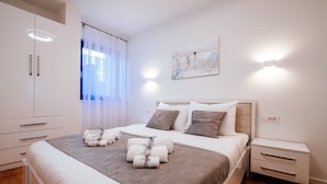 A modern bedroom with a large bed, bedside tables, a wardrobe, and a painting on the wall. - Deluxe Apartment Isabela Prague (Zadar)