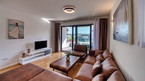 A modern living room with a flat-screen TV, a sofa set, a coffee table, and artwork on the walls. - Deluxe Apartment Isabela Prague (Zadar)