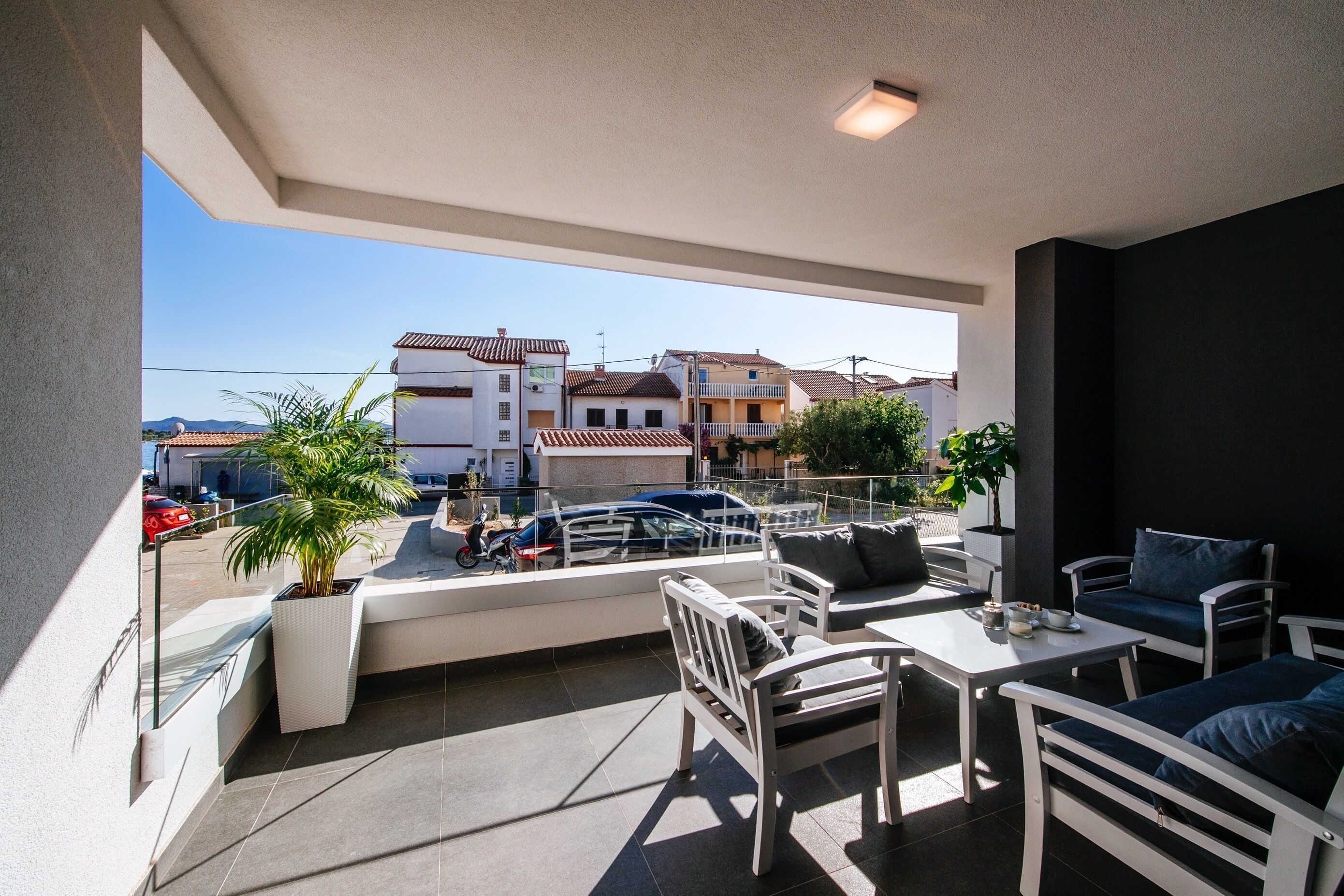 A balcony with a seating area, a view of the street, and a potted plant.