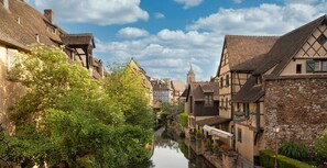Ein schmaler Kanal, gesäumt von traditionellen Fachwerkhäusern, mit einem Kirchturm im Hintergrund.