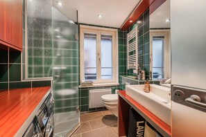 Ein modernes Badezimmer mit einer Duschkabine aus Glas, einer weißen Toilette und einem Holzbadezimmer-Möbel.