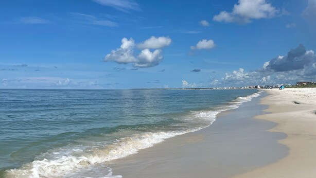 Ein Strand mit breitem Sandstrand und sanften Wellen.