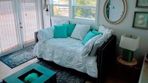 Ein Schlafzimmer mit Bett, Deckenventilator, Fenster, Spiegel und Lampe.