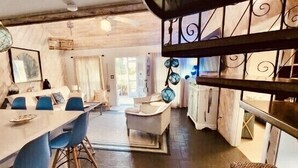 Ein gemütlicher Essbereich mit einem langen Tisch und blauen Stühlen, eine Treppe mit dekorativer Metallgeländer und Blick auf das angrenzende Wohnzimmer.