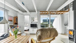 A cozy living room with a wooden table, a TV, and a fireplace. - Beautiful home in Hvide Sande with WiFi (Hvide Sande)