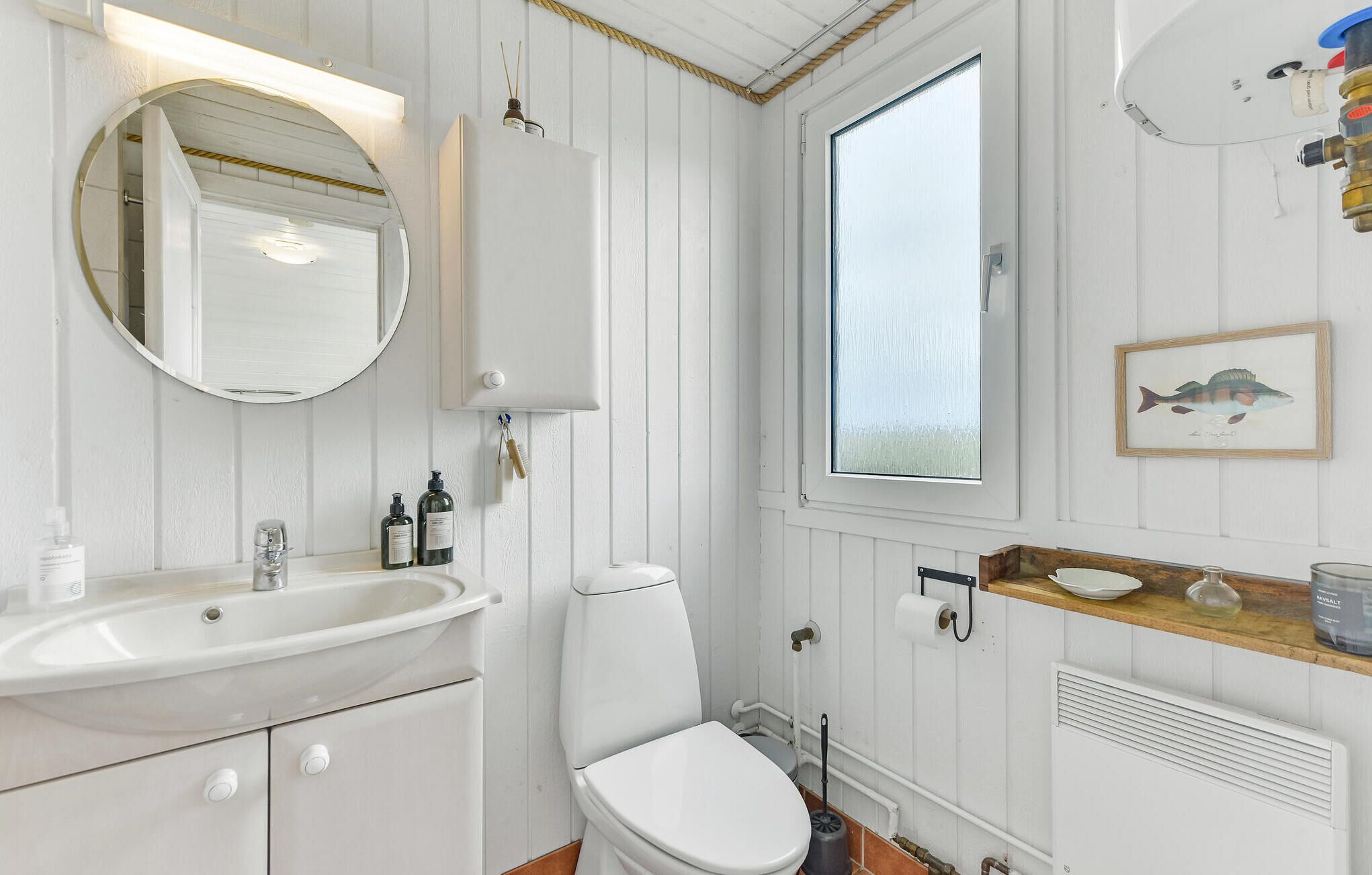 Ein Badezimmer mit Waschbecken, Spiegel, Toilette und einem Fenster.