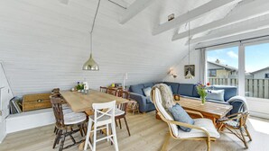A spacious living room with a wooden dining table, white chairs, a blue sofa, and a wooden coffee table. - Beautiful home in Hvide Sande with WiFi (Hvide Sande)