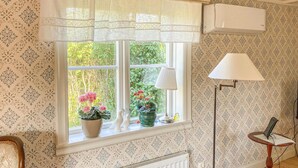 Et værelse med vindue, radiator, lampe og et lille bord.