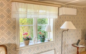 Relax in this serene room with a large window, potted plants, and a cozy floor lamp.