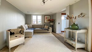 A living room with a sofa, a chair, a rug, and a console table with a vase. - 3 bedroom beautiful home in Hovås (Hovås)