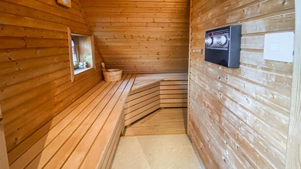 A sauna room with wooden walls and benches, a window, and a control panel. - 3 bedroom beautiful home in Hovås (Hovås)