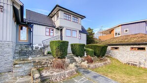 A two-story house with a stone foundation, a stone staircase, and a well-maintained garden with hedges and a statue. - 3 bedroom beautiful home in Hovås (Hovås)