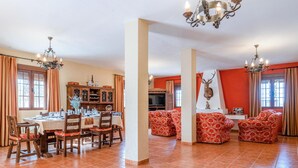 A dining area with a table set for four, surrounded by chairs. There is a television on a stand and a cabinet with decorative items. - Amazing home in Lucena (Lucena)